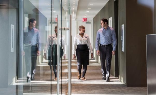 Two employees walking and talking in an office hallway