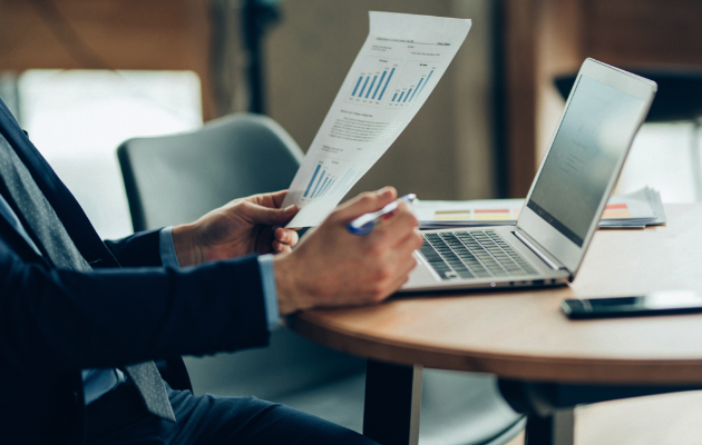 Financial professional analyzing graphs in front of a laptop