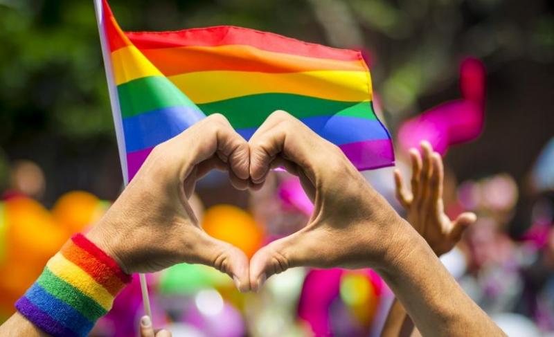 Person making a heart with their hands at a Pride event