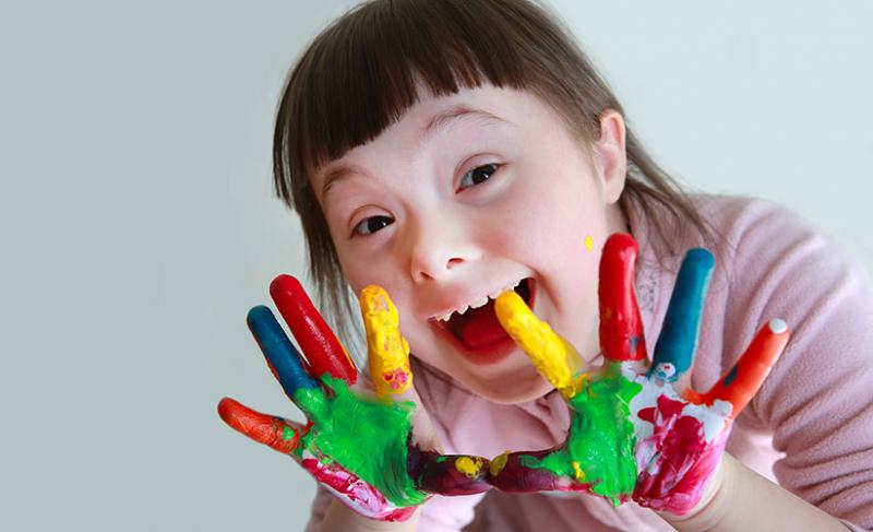 A young child with colorful paint on her hands